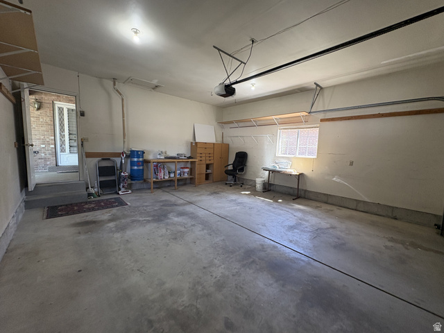 486 West 120 North Orem, UT 84057 - Photo 28 of 30 Spacious 2 car garage featuring a concrete floor, overhead lighting, an interior access door, a transom window, and built-in shelving