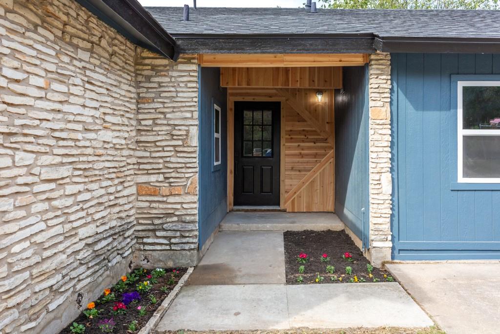 9604 Crown Ridge Road Austin, TX 78753 - Photo 2 of 24 A welcoming entry combines stone and cedar accents, complemented by colorful landscaping.