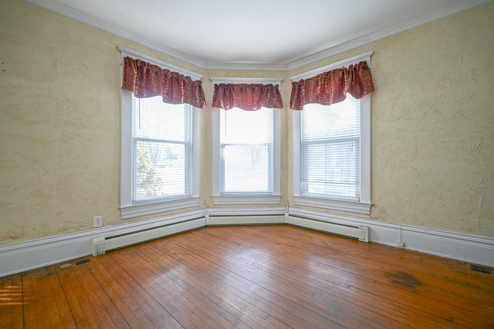 408 South 5th Street Oregon, IL 61061 - Photo 19 of 43 an empty room with wooden floor and windows with curtains view