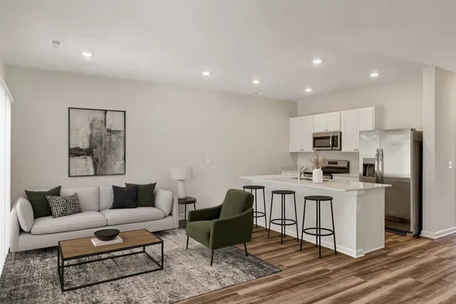 a living room with stainless steel appliances furniture and a kitchen view