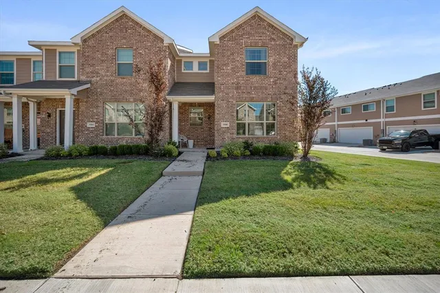 a view of a brick house with a yard and many windows