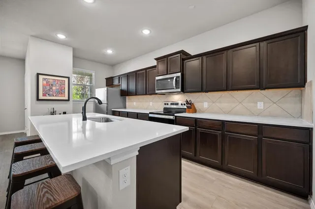 a kitchen with kitchen island white cabinets sink and stainless steel appliances