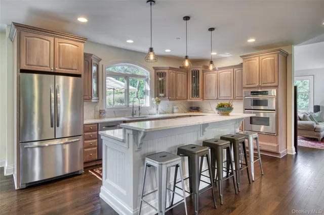 a kitchen with stainless steel appliances granite countertop a refrigerator a stove a sink a dining table and chairs with wooden floor