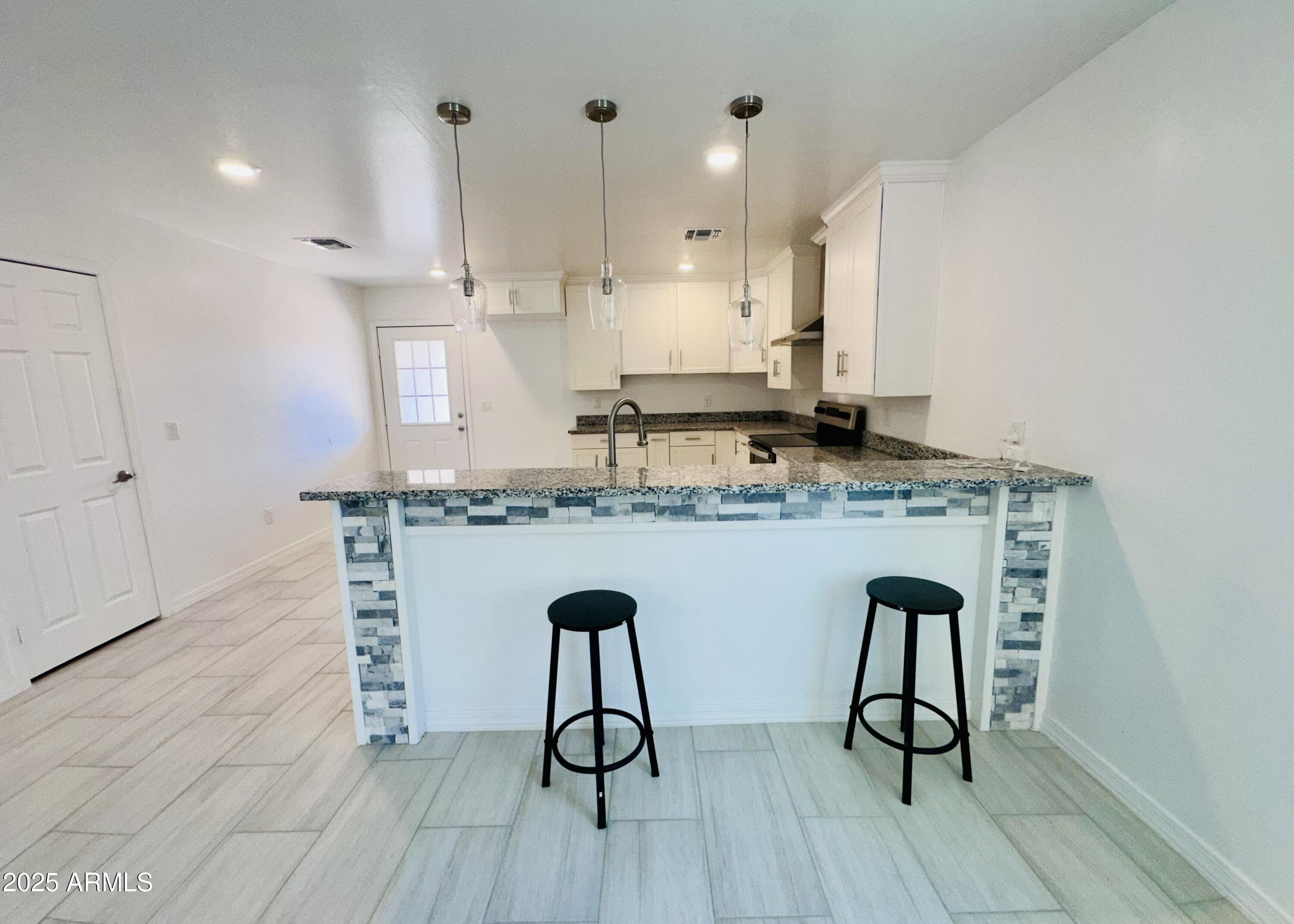 32007 North Bush Street Wittmann, AZ 85361 - Photo 9 of 22 a kitchen with stainless steel appliances granite countertop a stove a sink and white cabinets with wooden floor