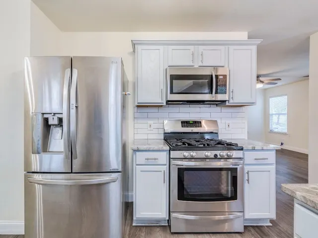 a kitchen with stainless steel appliances white cabinets a stove top oven a sink and dishwasher