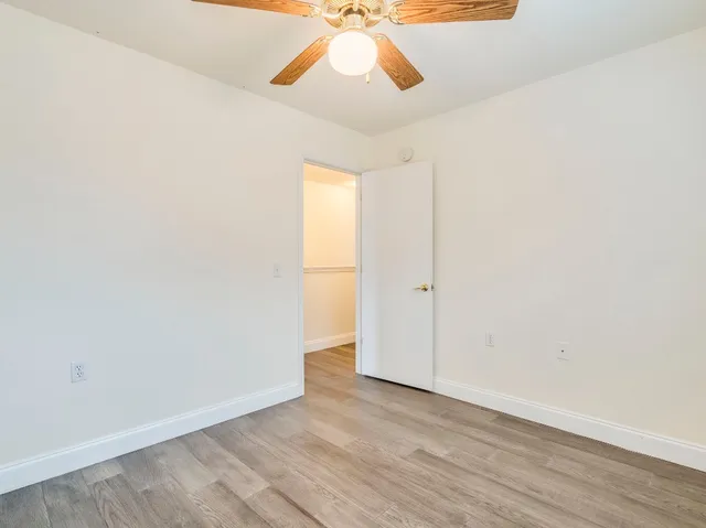 an empty room with a window and a chandelier fan