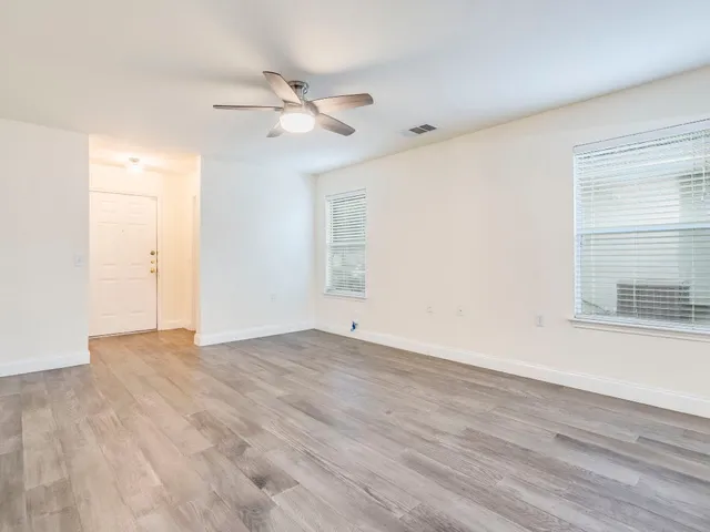 a view of an empty room with wooden floor and a window
