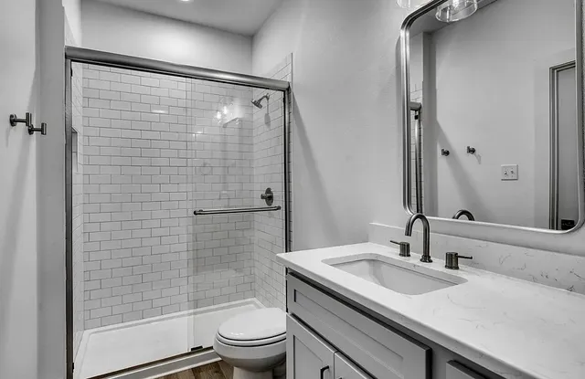 a bathroom with a granite countertop sink toilet and shower