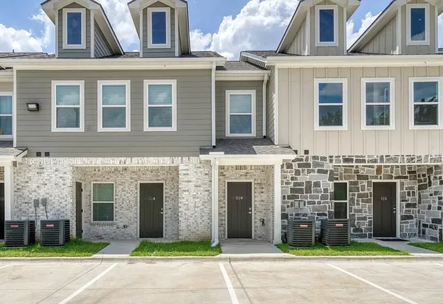 a front view of a building with a garden and plants