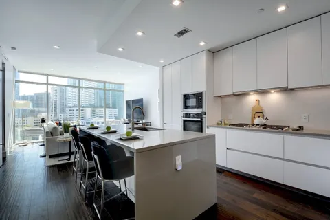 a kitchen with sink a stove and white cabinets with wooden floor
