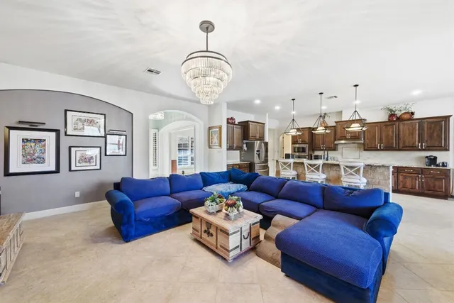 a living room with furniture kitchen view and a chandelier