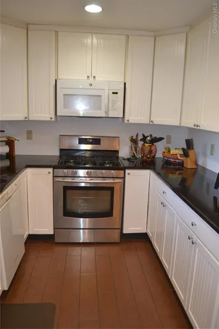 a kitchen with granite countertop white cabinets and white appliances