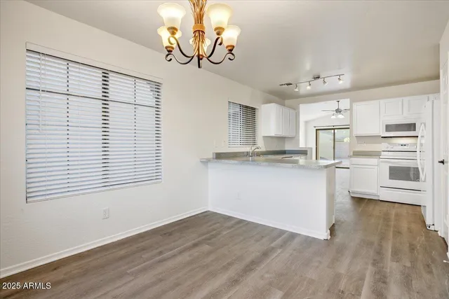 a kitchen with granite countertop stainless steel appliances cabinets a large window and a wooden floor