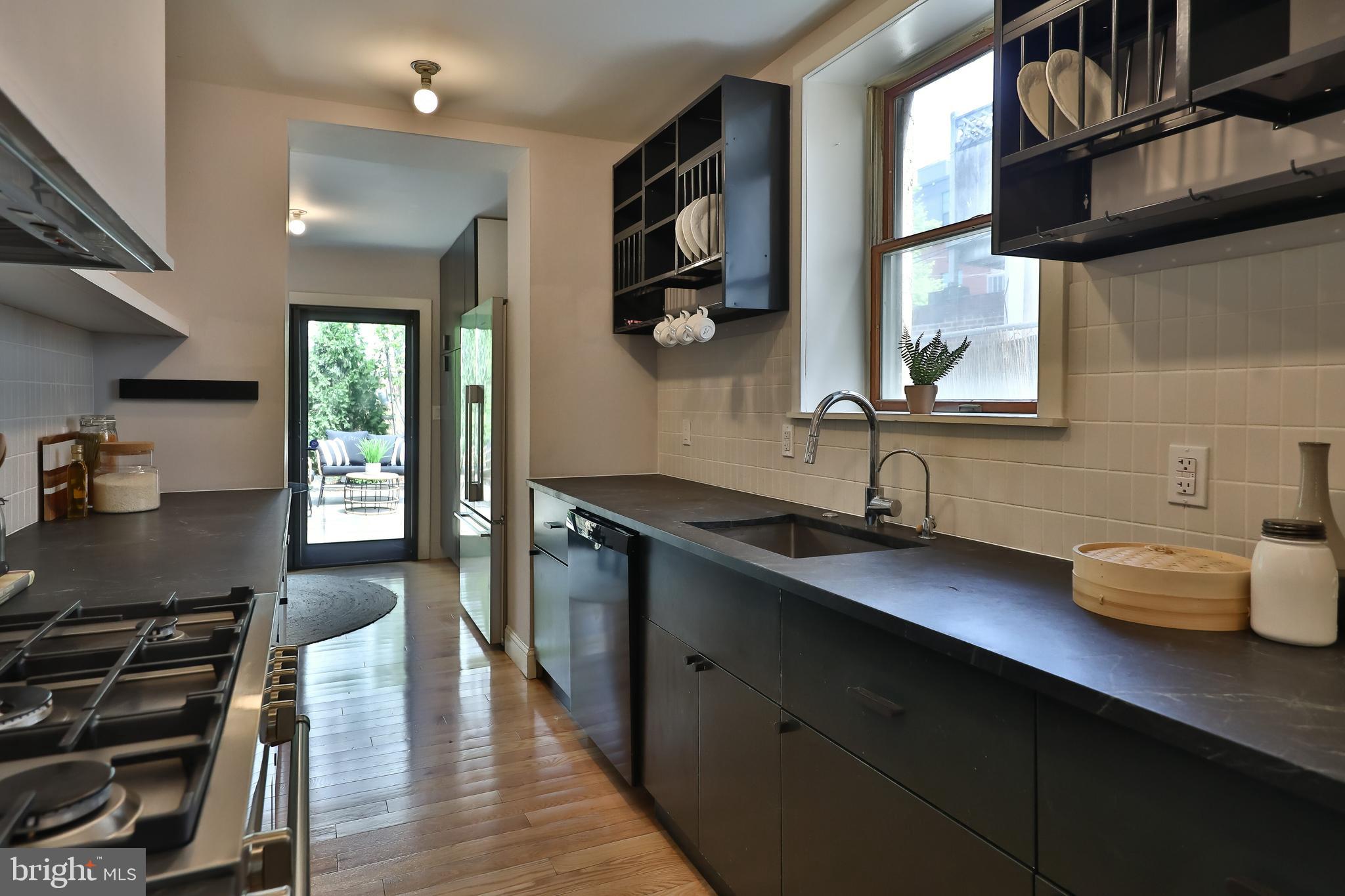 2805 Poplar Street Philadelphia, PA 19130 - Photo 12 of 34 a kitchen with stainless steel appliances a sink dishwasher a stove a dining table and chairs with wooden floor