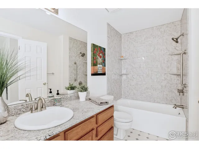 a bathroom with a granite countertop sink a toilet a mirror and shower