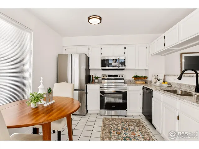 a kitchen with stainless steel appliances a stove a sink a microwave a dining table and chairs