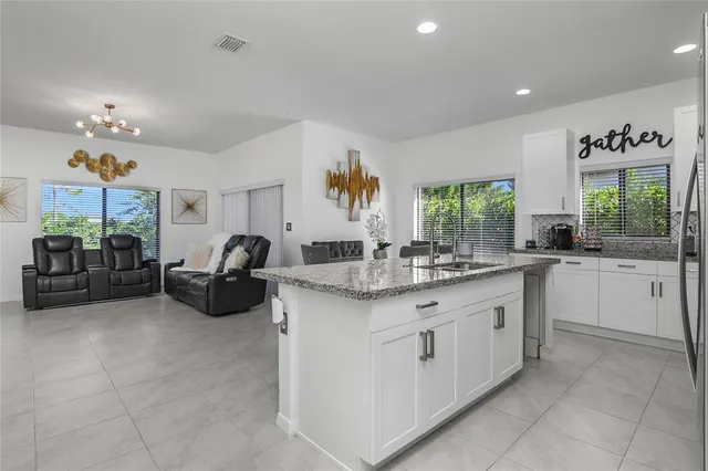 a kitchen with stainless steel appliances granite countertop a refrigerator a sink a stove a dining table and chairs