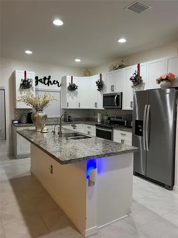 a kitchen with stainless steel appliances granite countertop a sink a stove and a refrigerator
