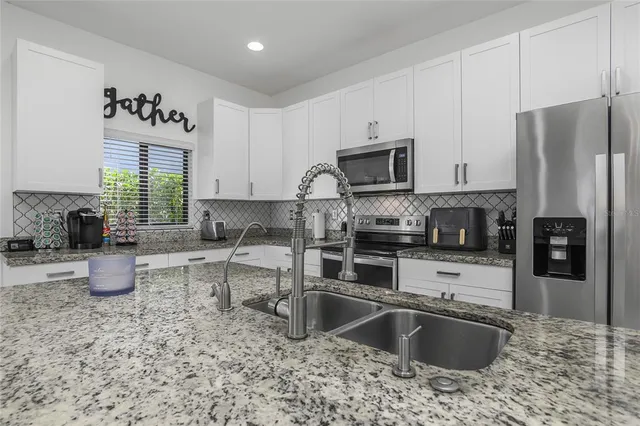 a kitchen with stainless steel appliances granite countertop a stove a sink and a refrigerator