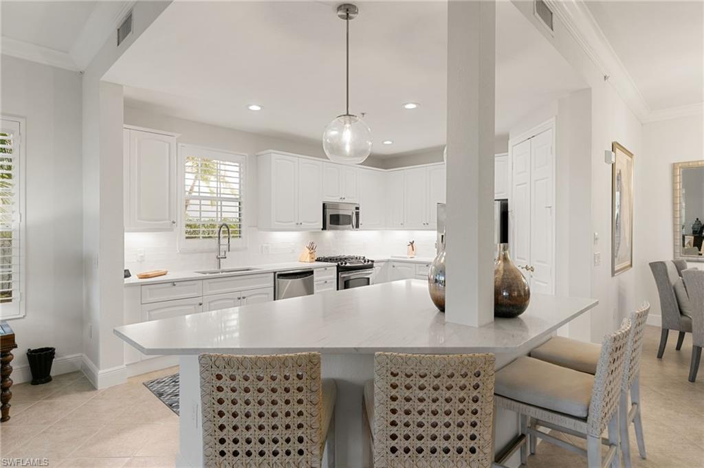 9082 Cascada Way, Unit 9102 Naples, FL 34114 - Photo 6 of 39 a kitchen with a dining table chairs and white cabinets