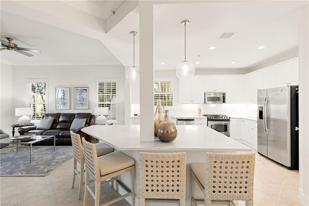 9082 Cascada Way, Unit 9102 Naples, FL 34114 - Photo 7 of 39 a kitchen with stainless steel appliances granite countertop a dining table chairs and white cabinets
