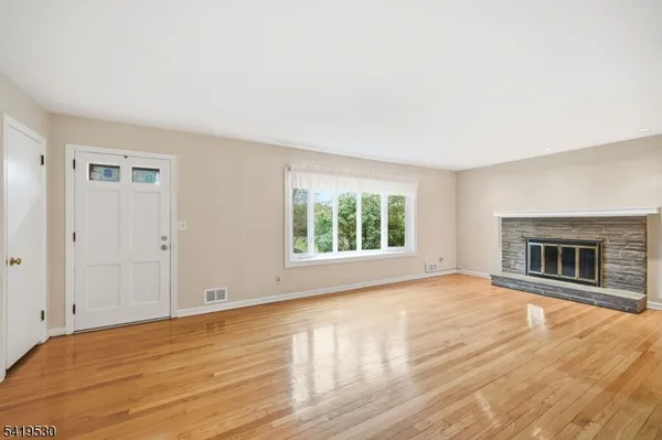 a view of empty room with wooden floor and fireplace