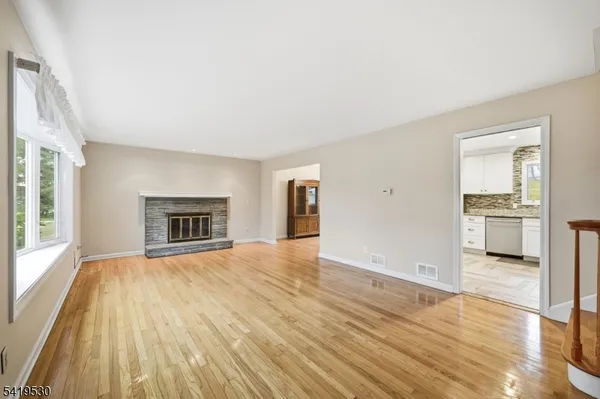a view of empty room with wooden floor and kitchen view