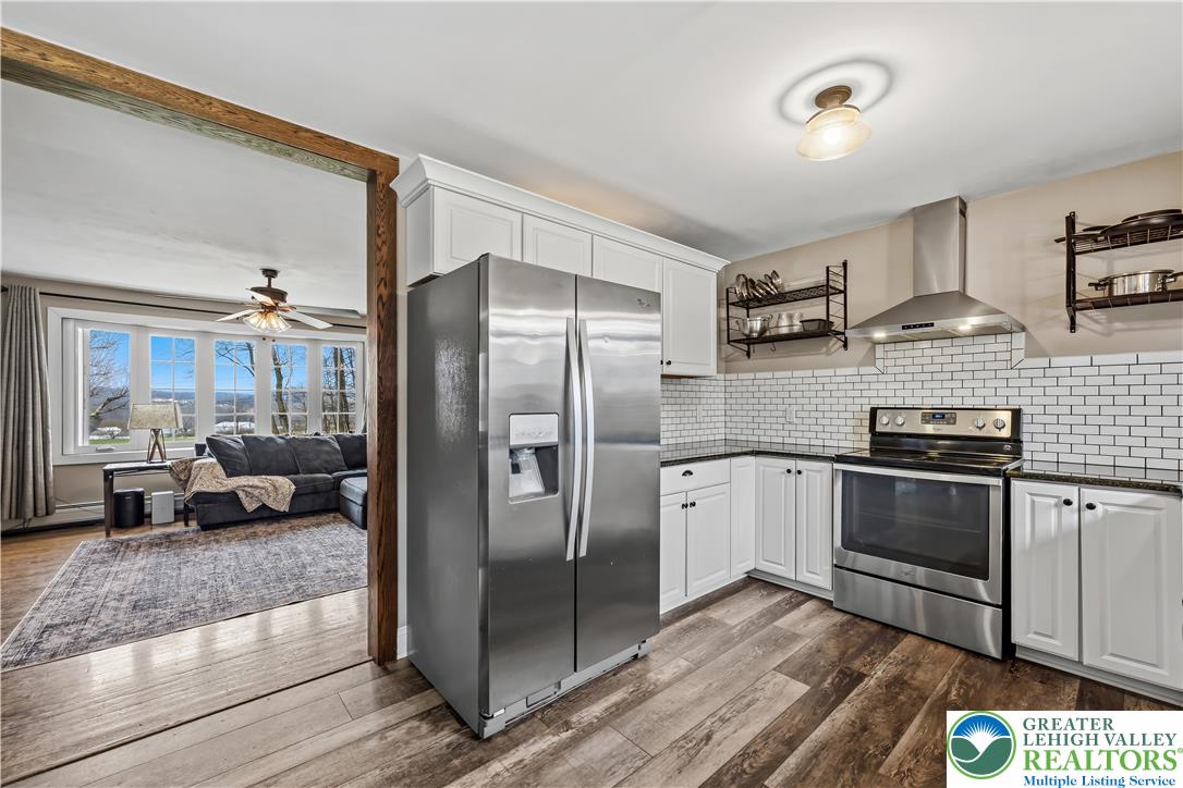 7462 Camp Meeting Road New Tripoli, PA 18066 - Photo 6 of 18 a kitchen with stainless steel appliances granite countertop a refrigerator a stove and a sink with wooden floor