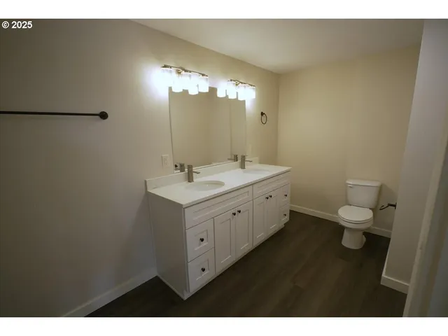 a bathroom with a double vanity sink toilet and a mirror