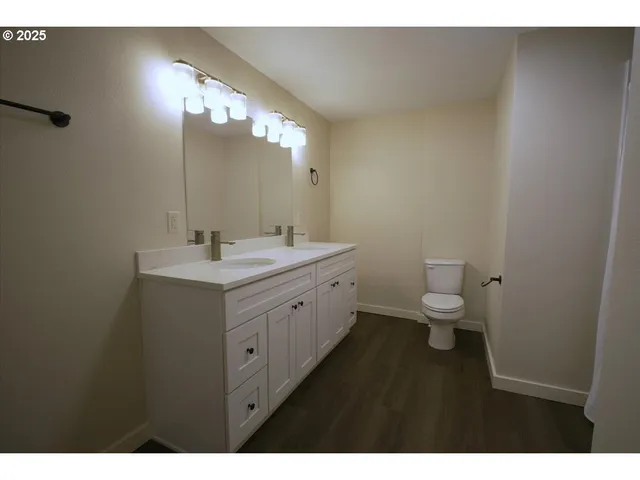 a bathroom with a double vanity sink a toilet and a mirror
