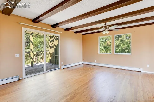 a view of an empty room with wooden floor and a fireplace