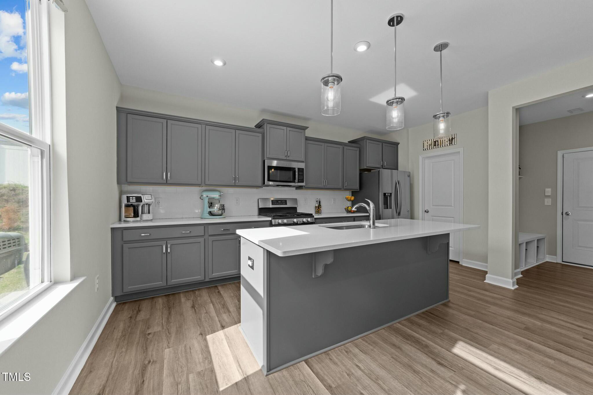 118 Lockhaven Drive Garner, NC 27529 - Photo 11 of 56 a kitchen with kitchen island a sink dishwasher a stove and white countertops with wooden floor