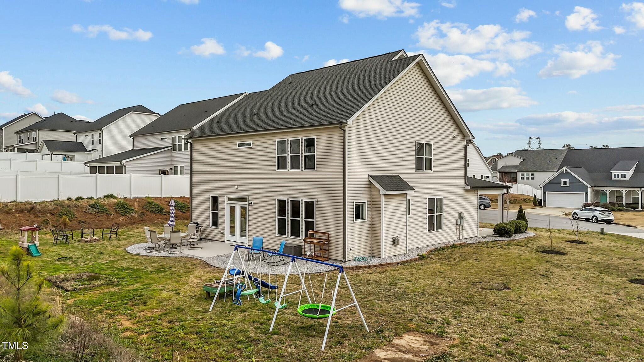 118 Lockhaven Drive Garner, NC 27529 - Photo 39 of 56 a view of a white house next to a yard with lawn chairs and a table