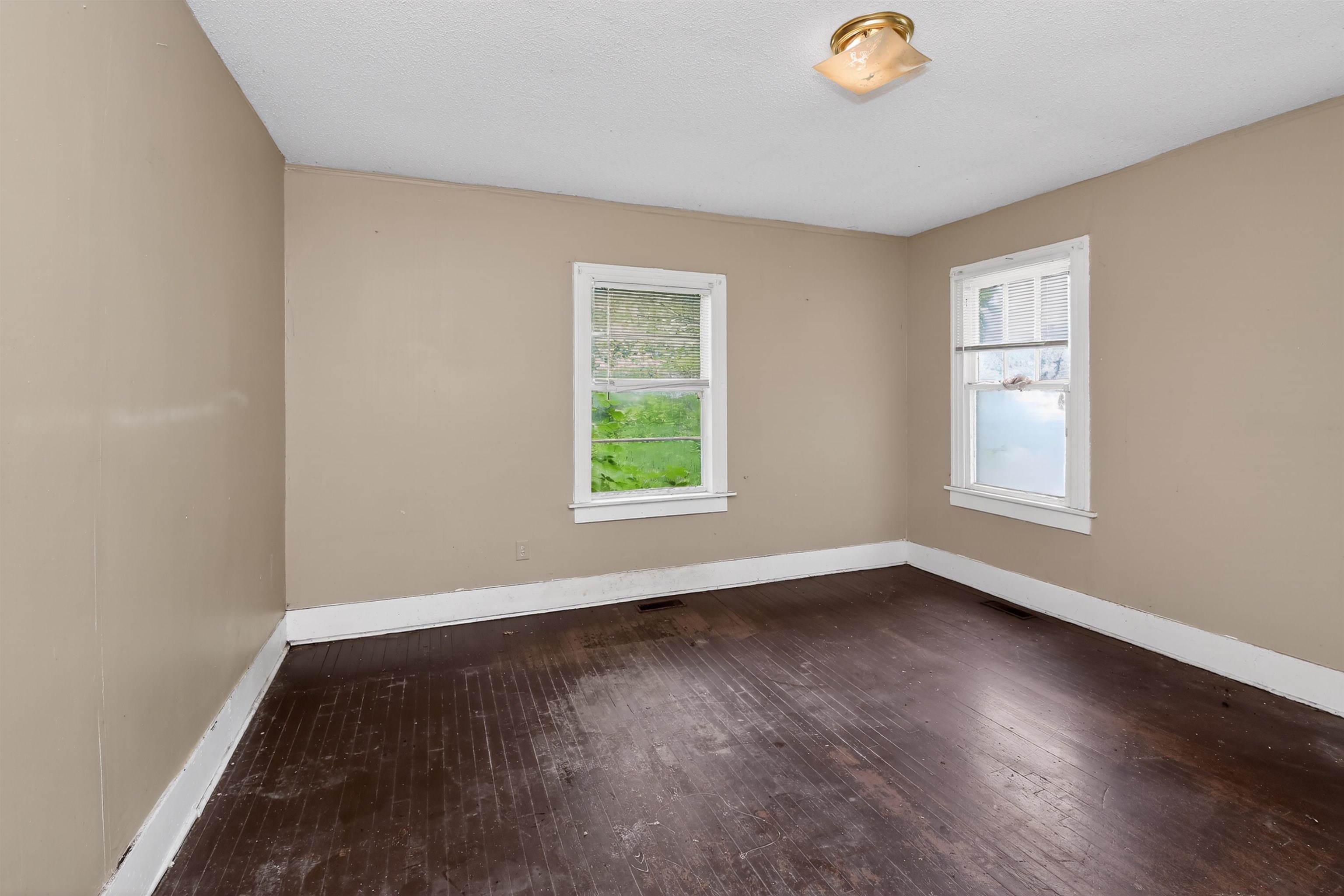 810 Hale Road Memphis, TN 38116 - Photo 9 of 30 Room featuring wood-finish flooring, two windows with white trim, tan painted walls, white baseboards, and a flush-mount ceiling light fixture