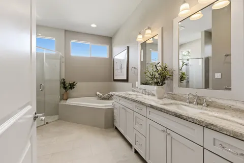 a bathroom with a granite countertop double vanity sink a mirror and a bathtub