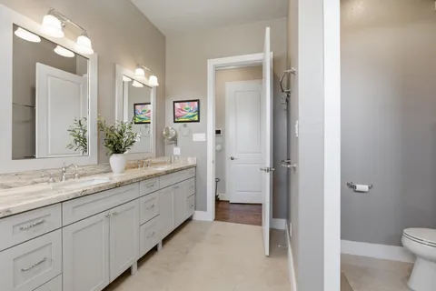 a bathroom with a granite countertop sink mirror and toilet