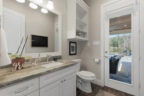 a bathroom with a granite countertop toilet sink and mirror