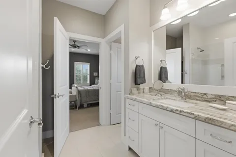 a en suite bathroom with a granite countertop sink and mirror