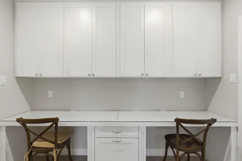 a room with a chair and white cabinets