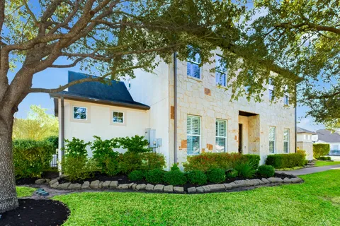 a view of a white house next to a yard with plants and trees