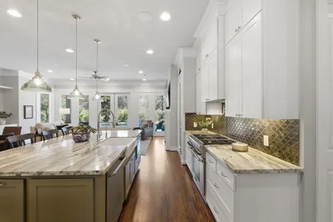 a kitchen with stainless steel appliances granite countertop a sink a stove and a wooden floors