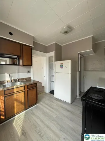 a kitchen with a refrigerator a stove top oven a sink and dishwasher with wooden floor