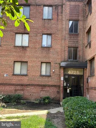 a view of a brick house with a yard and a large tree