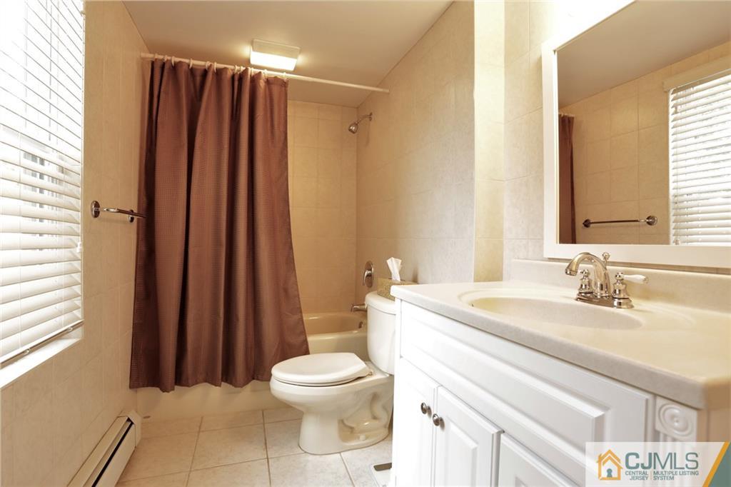 18 Homestead Road Freehold, NJ 07728 - Photo 9 of 32 a bathroom with a sink a toilet a mirror and shower curtain