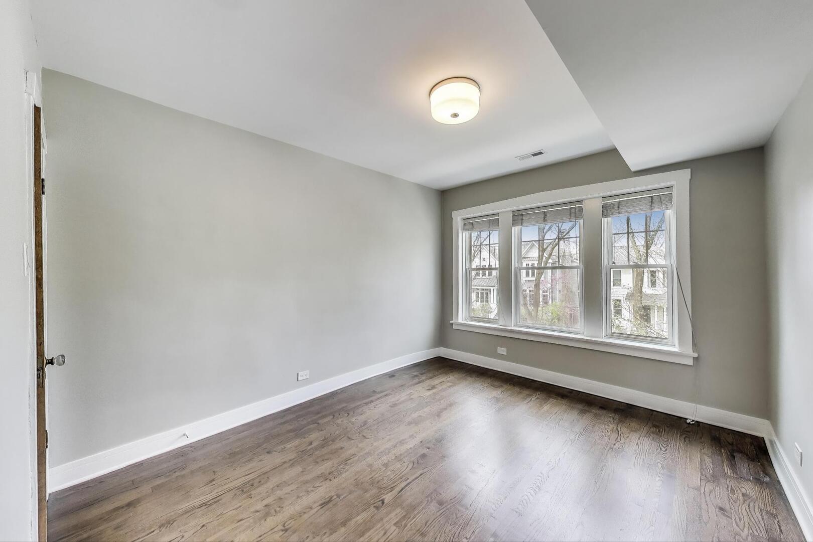 1451 West Warner Avenue, Unit 2 Chicago, IL 60613 - Photo 13 of 23 an empty room with wooden floor and windows