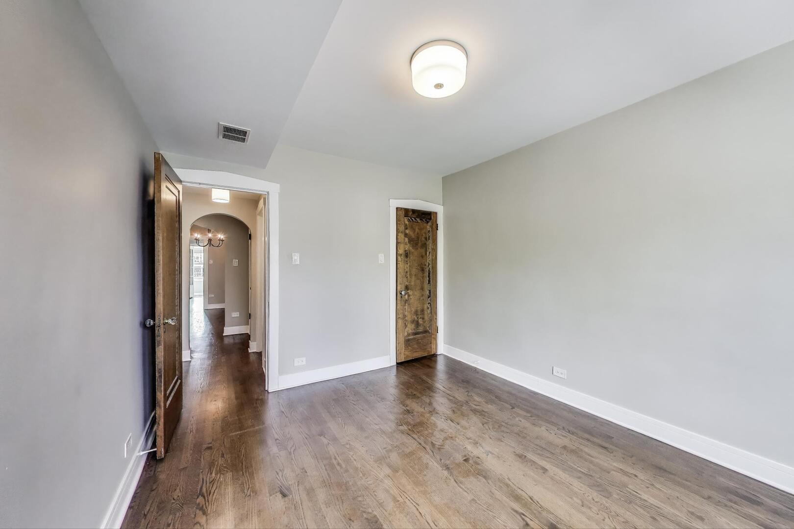 1451 West Warner Avenue, Unit 2 Chicago, IL 60613 - Photo 14 of 23 an empty room with wooden floor and mirror