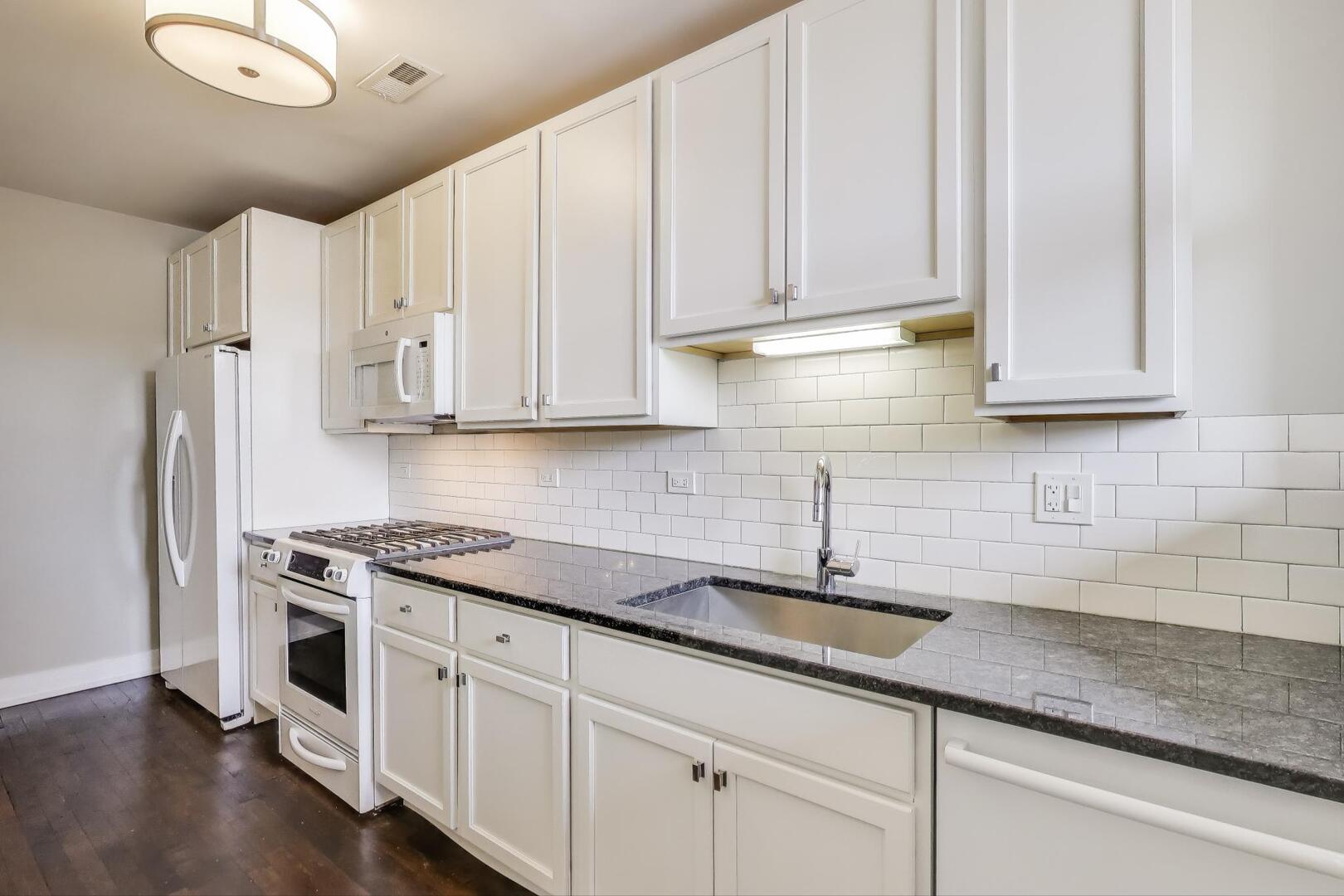 1451 West Warner Avenue, Unit 2 Chicago, IL 60613 - Photo 10 of 23 a kitchen with stainless steel appliances granite countertop white cabinets and a sink