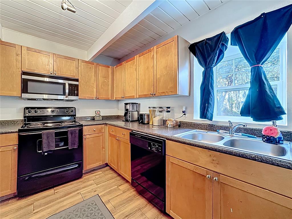 772 East Michigan Street, Unit 70 Orlando, FL 32806 - Photo 11 of 54 a kitchen with stainless steel appliances granite countertop a sink a stove a microwave and wooden cabinets