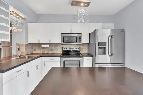 a kitchen with kitchen island a counter top space cabinets stainless steel appliances and a window