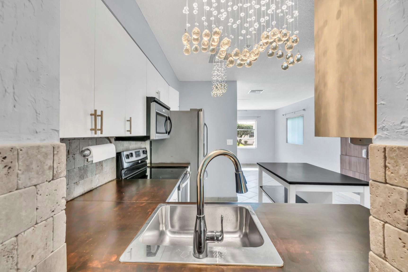 7115 Northwest 73rd Street Tamarac, FL 33321 - Photo 17 of 46 a kitchen with a table chairs and chandelier